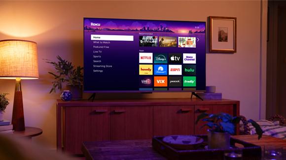 Fotografia ufficiale Roku di un televisore e dell’interfaccia di streaming in un soggiorno.