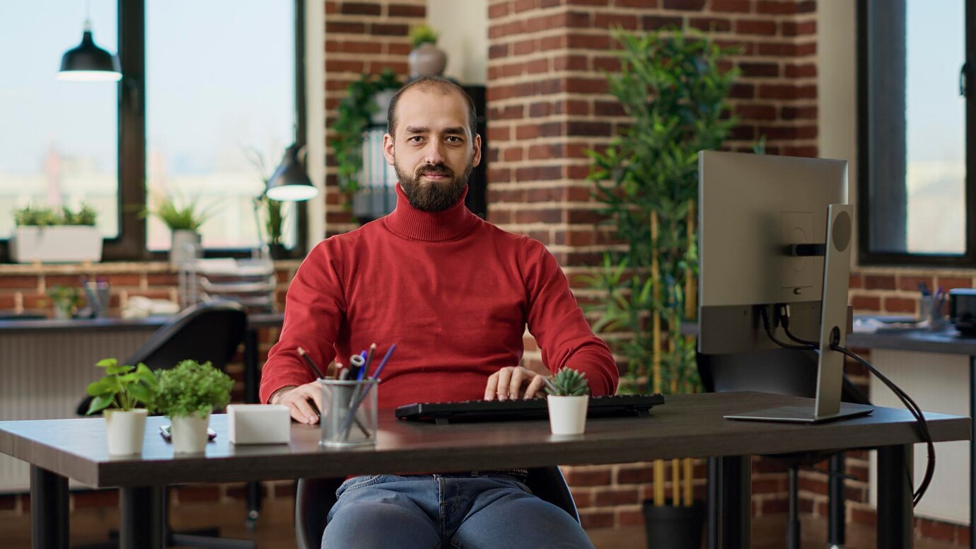 Portrait of businessman sitting at desk and preparing to work on computer